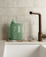 Ecoya Wild Sage and Citrus laundry liquid styled in a laundry with folded linen