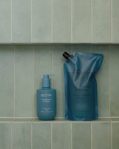 Ecoya Sandalwood & Amber refill pouch and bottle in a green tiled shower niche
