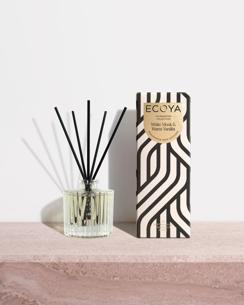 Ecoya Celebration diffuser and gift box on a pink stone surface against a pale wall