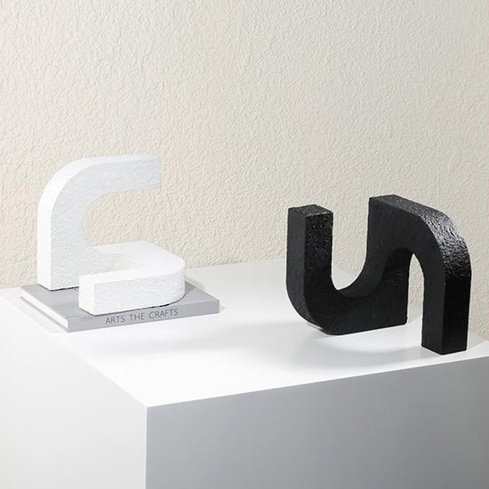 White and black versions of the arch ornament displayed on a pale plinth