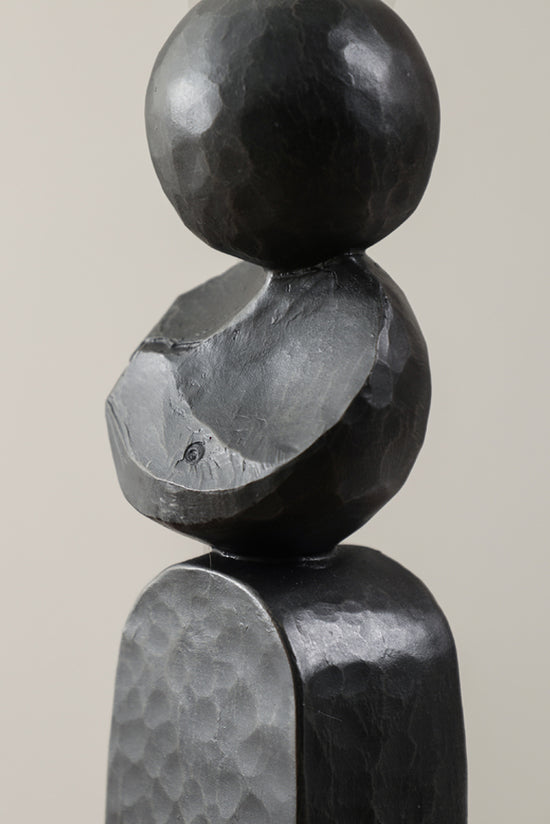 Close up of the black Pillar sculpture showing the carved and hammered stone finish