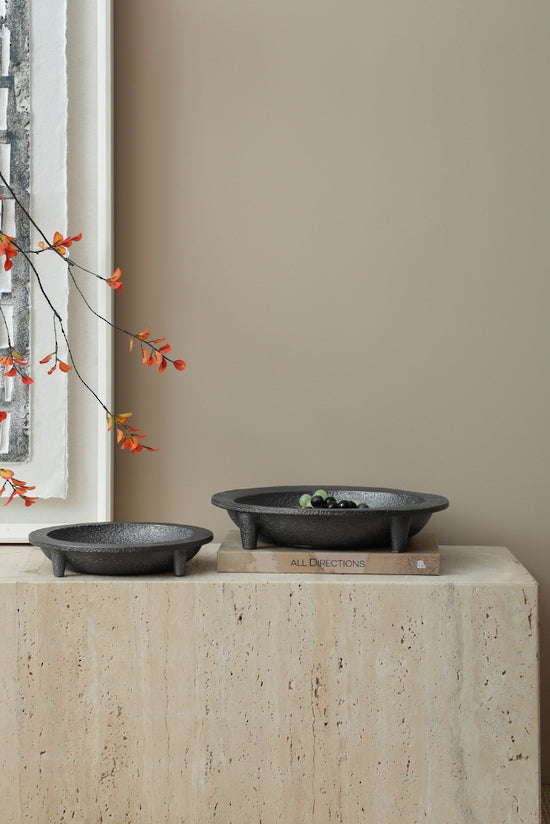 Small and large Friars cement tripod plates on a travertine plinth by a window