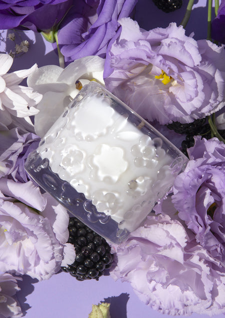 The Purple Reign candle on its side among purple lisianthus and ripe blackberries