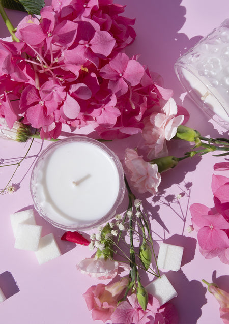 Flat lay of the Sugared Rose candle on pink with hydrangea, sugar cubes and pale roses