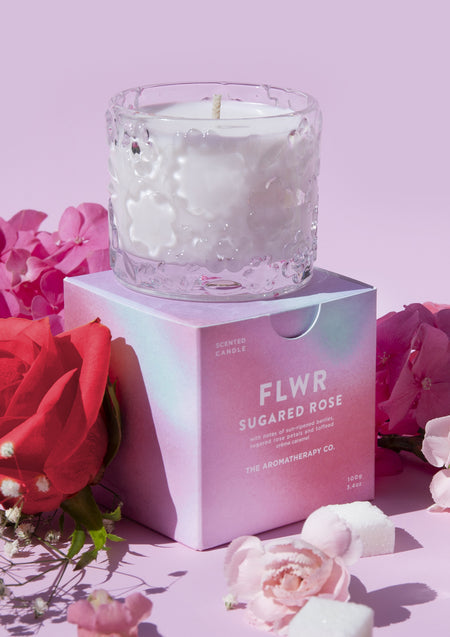 The Sugared Rose candle resting on its pink carton with red and pink roses and sugar cubes