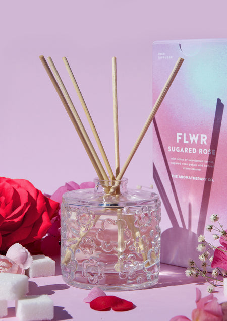 The Sugared Rose diffuser with its carton, red roses and sugar cubes on a lilac backdrop