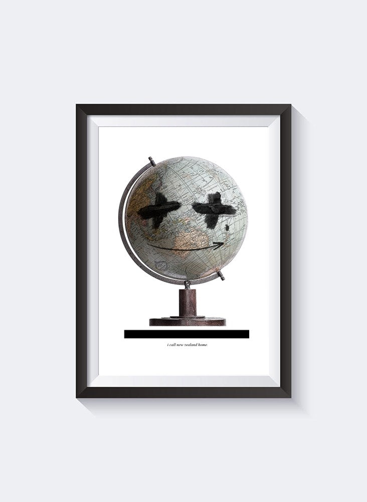 NZ Home Globe A3 print by Federation, grey globe painted with crossed eyes and a smile, shown in a black frame