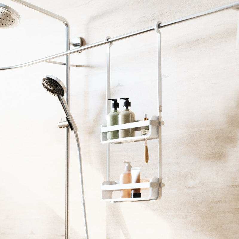 White Flex shower caddy hung from a shower rail beside a handheld shower, holding pump bottles
