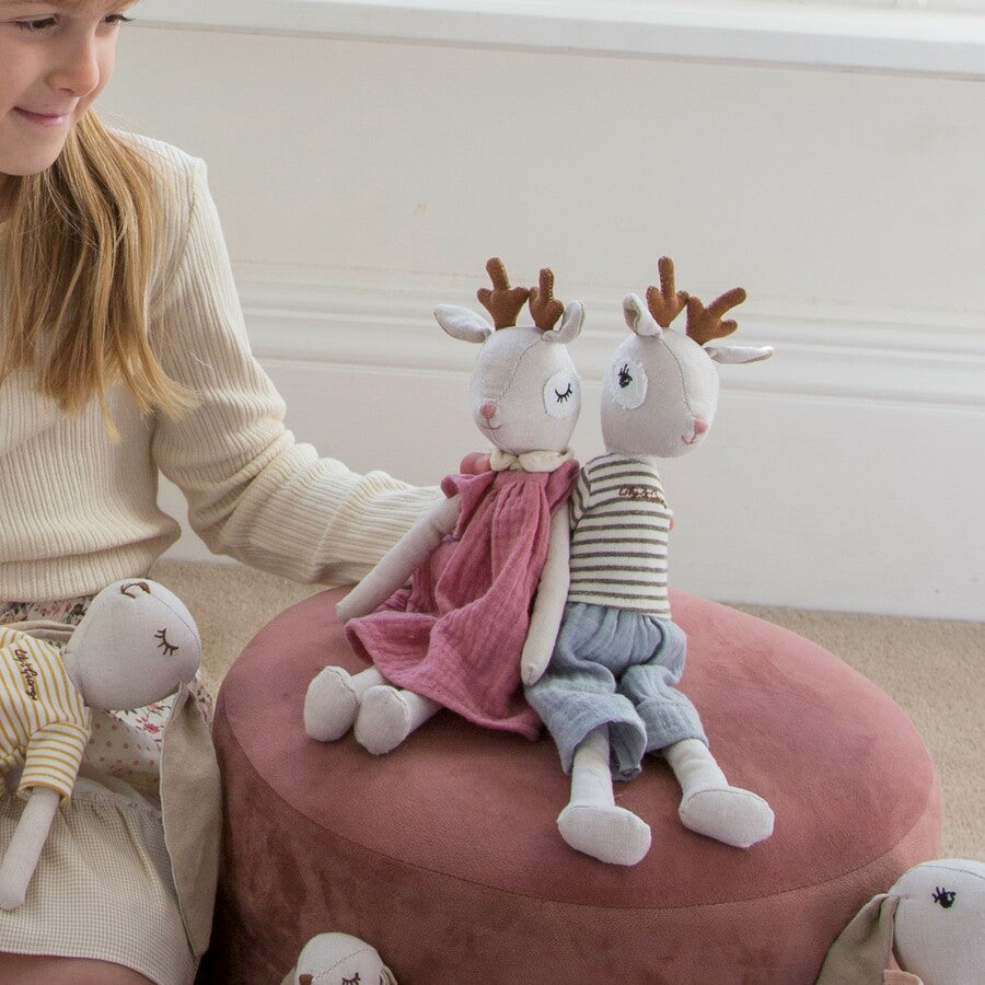 Two deer dolls in striped and pink outfits sitting on a pink pouf