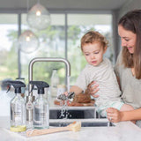 A woman and child washing dishes using the Good Change kitchen spray bottle.