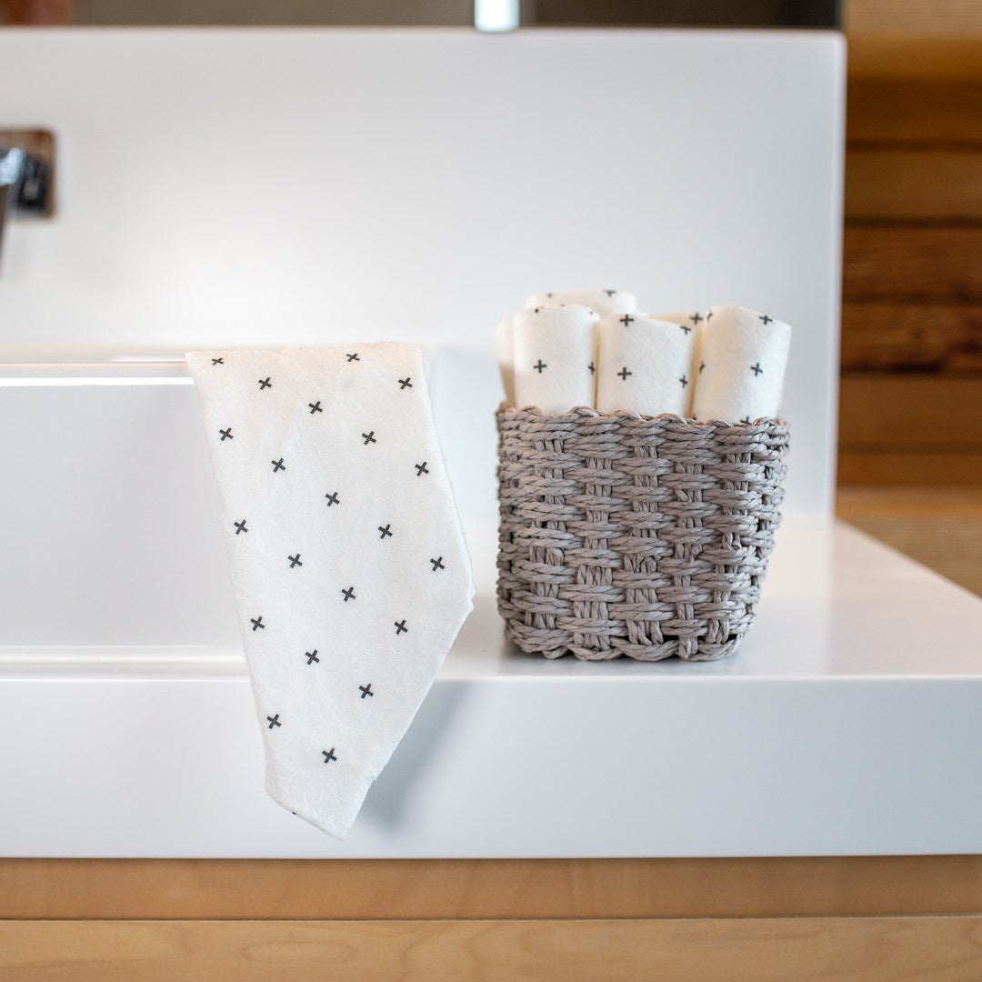 An eco-friendly bathroom sink with a basket of Good Change reusable bamboo towels.