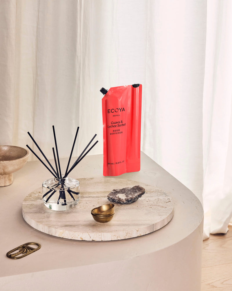 Ecoya Guava and Lychee Sorbet reed diffuser with its red refill pouch on a travertine tray