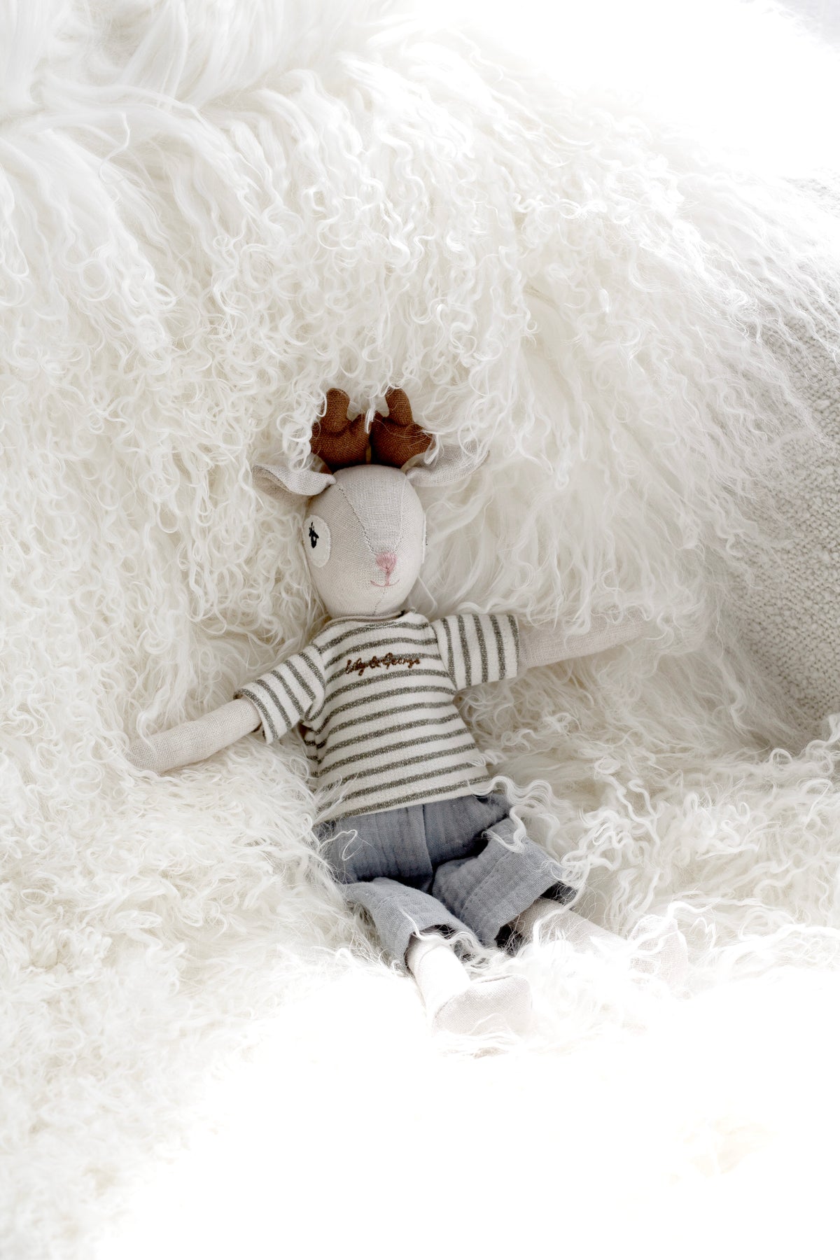 Gabriel the Deer doll lying on white sheepskin