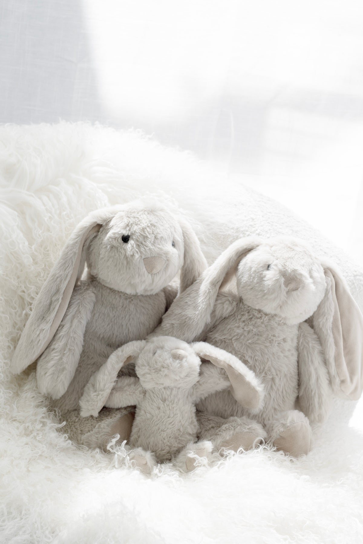 Three Thumper bunnies of different sizes nestled on white sheepskin