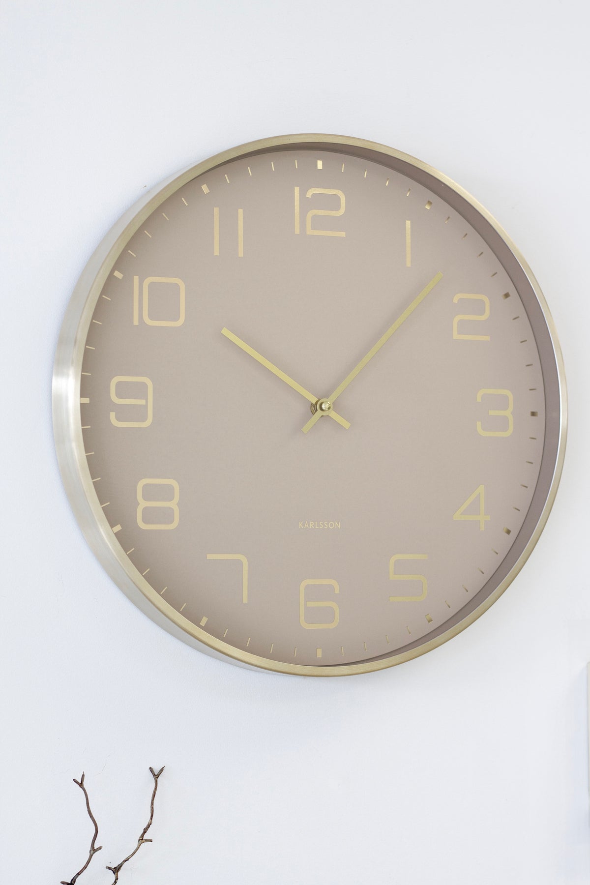 Karlsson Elegance Glow in soft brown on a white wall above wall hooks