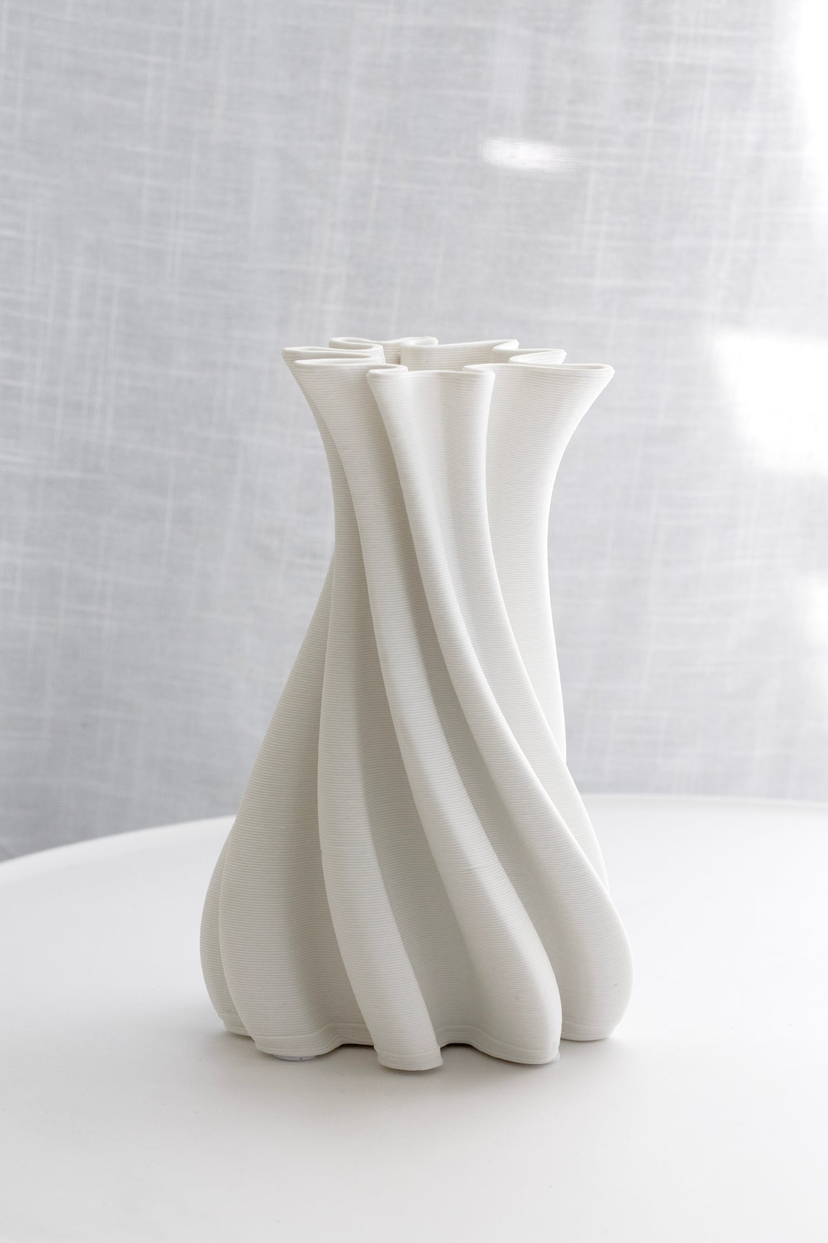 White Camila vase on a round white table in soft shadow