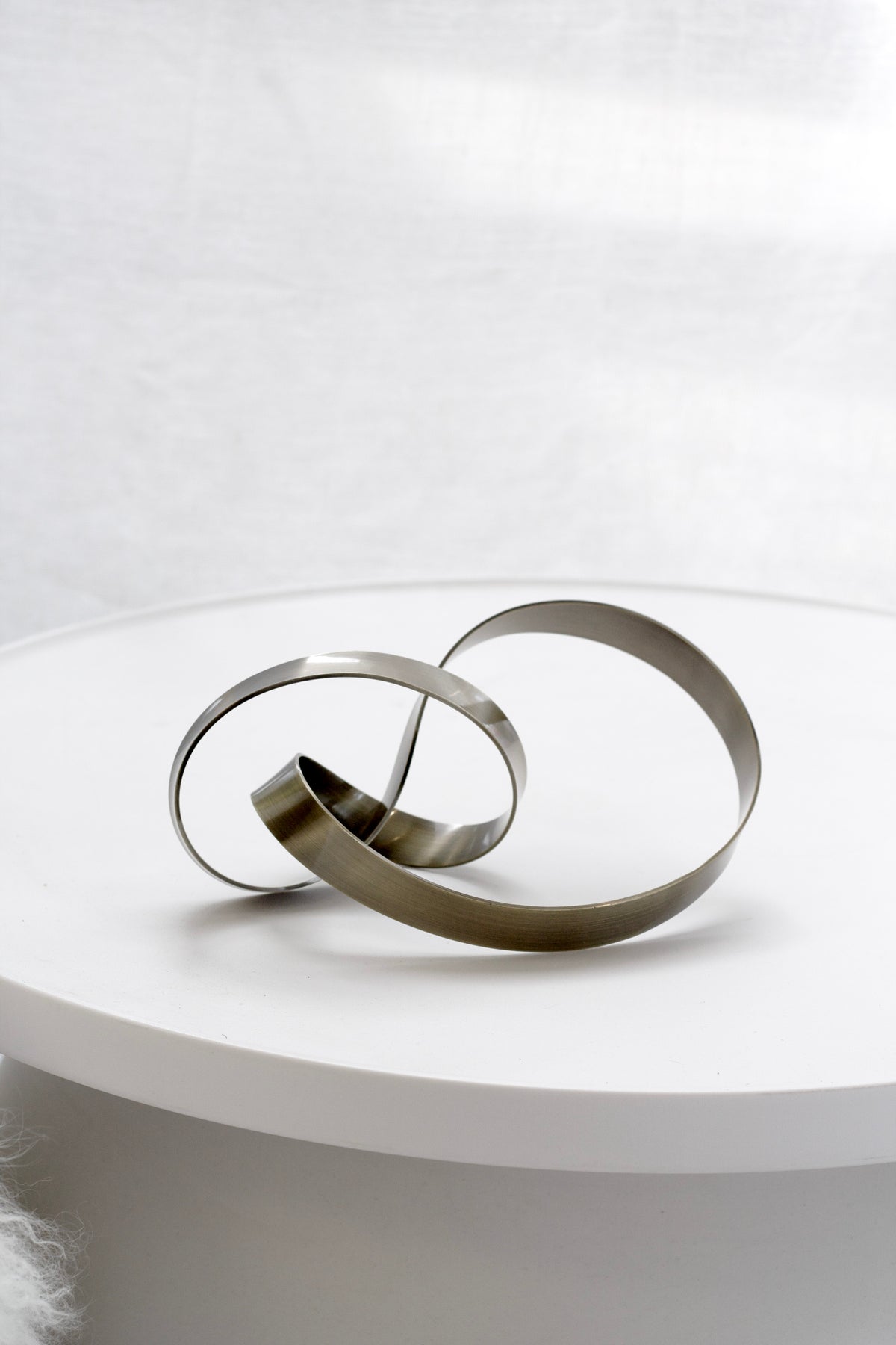 Bronze Infinity Loop sculpture on a round white side table