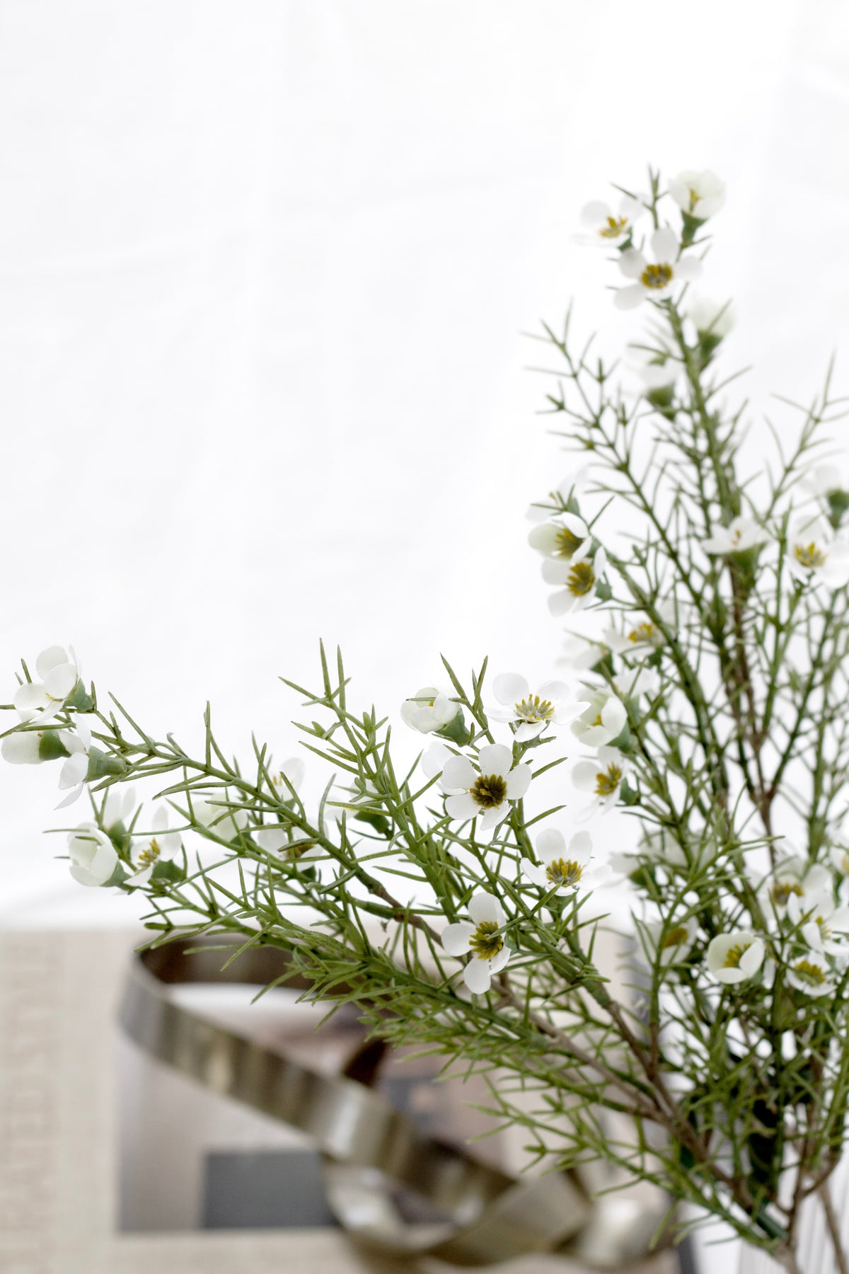 Wax flower spray beside a white gift box with silver ribbon