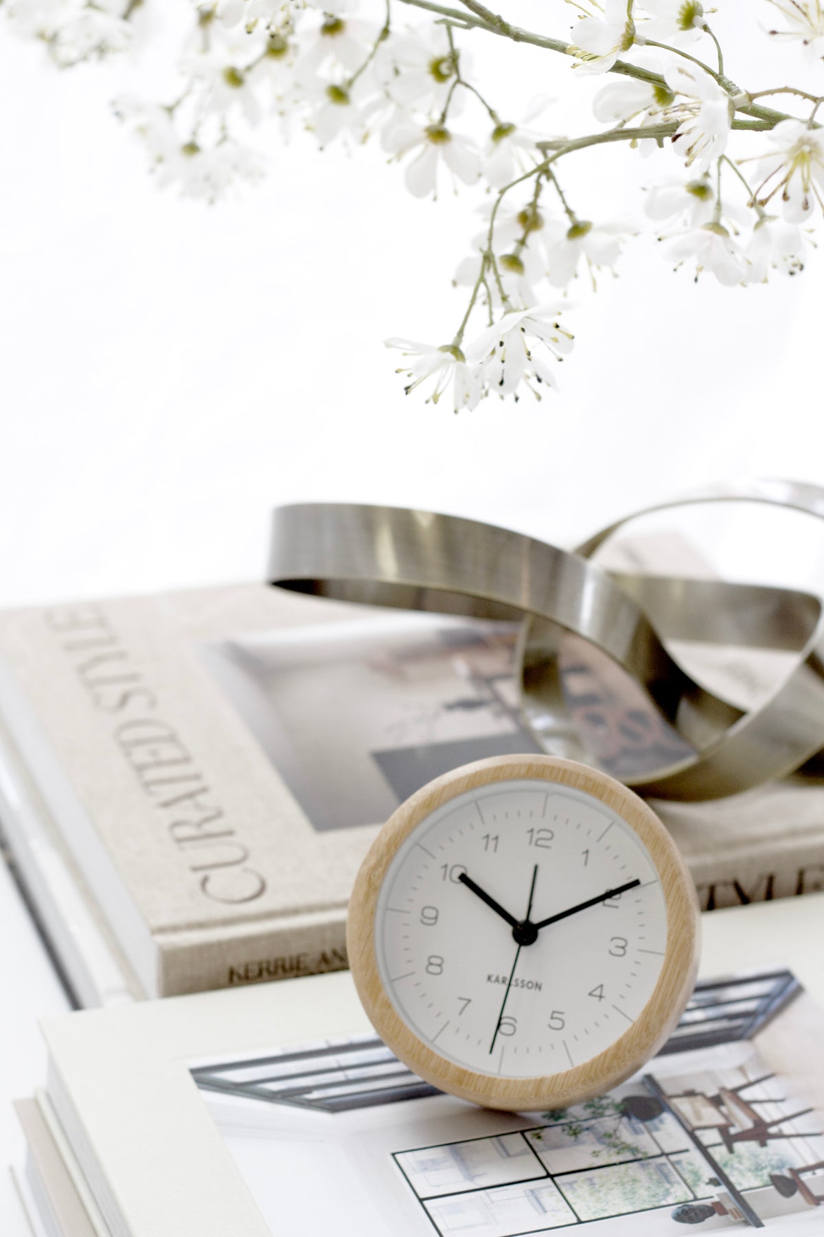 Karlsson Neat Round Bamboo Alarm Clock styled on a bedside surface