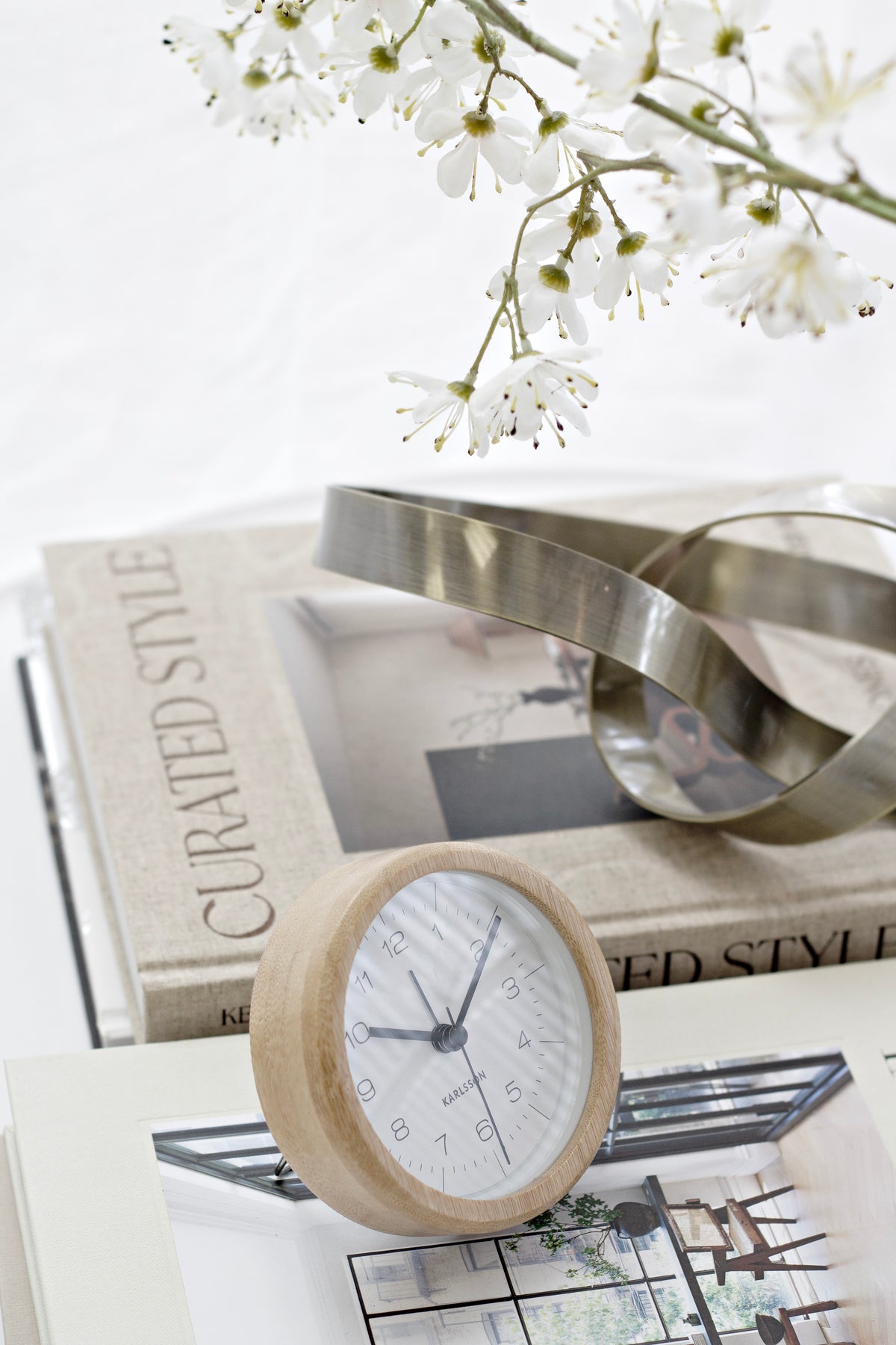 Karlsson Neat Round Bamboo Alarm Clock styled on a stack of books