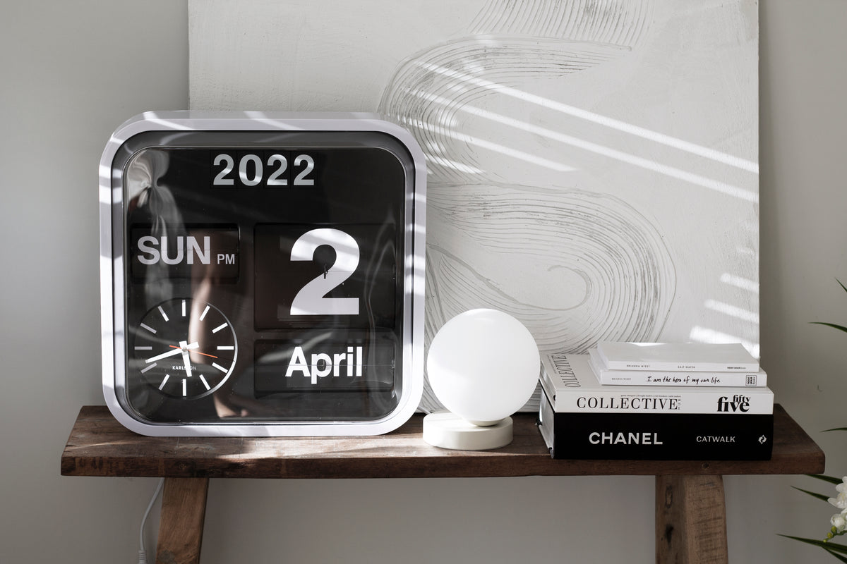 A Yuri Table lamp by Ned Collections on a shelf with a soft glow emitted by LED bulbs.