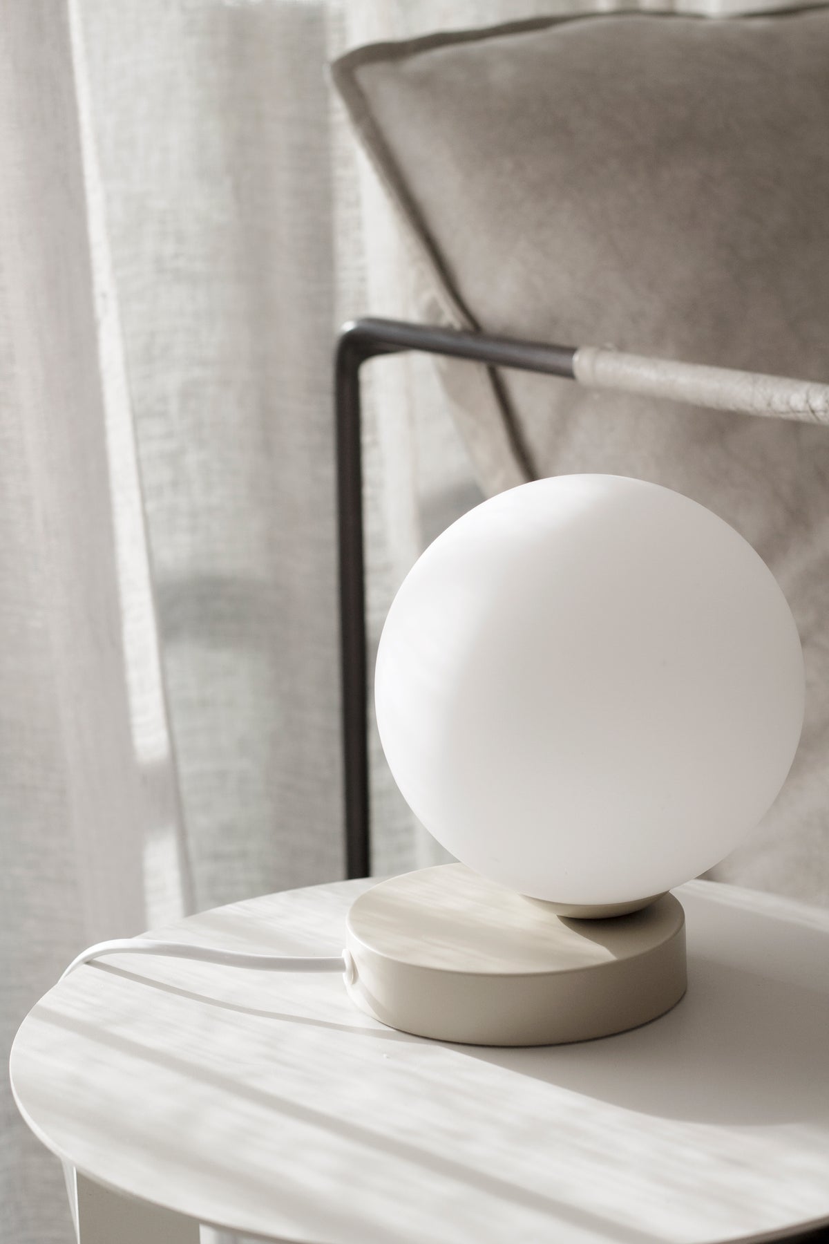 A Yuri Table lamp from Ned Collections with LED bulbs casts a soft glow on a table next to a couch.