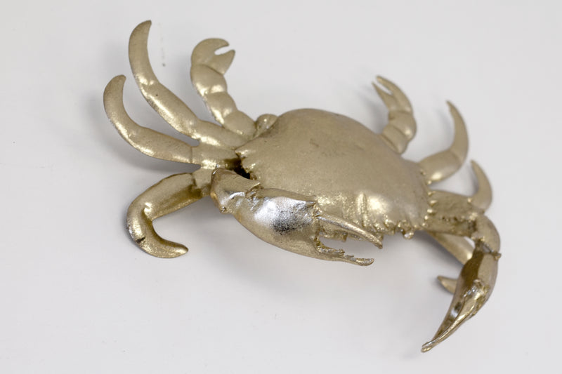 A Flux Home Crab Ornament - Gold hanging on a white wall showcasing its depth.