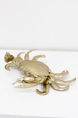 A Flux Home Brass Crab Ornament - Gold with a white surface.