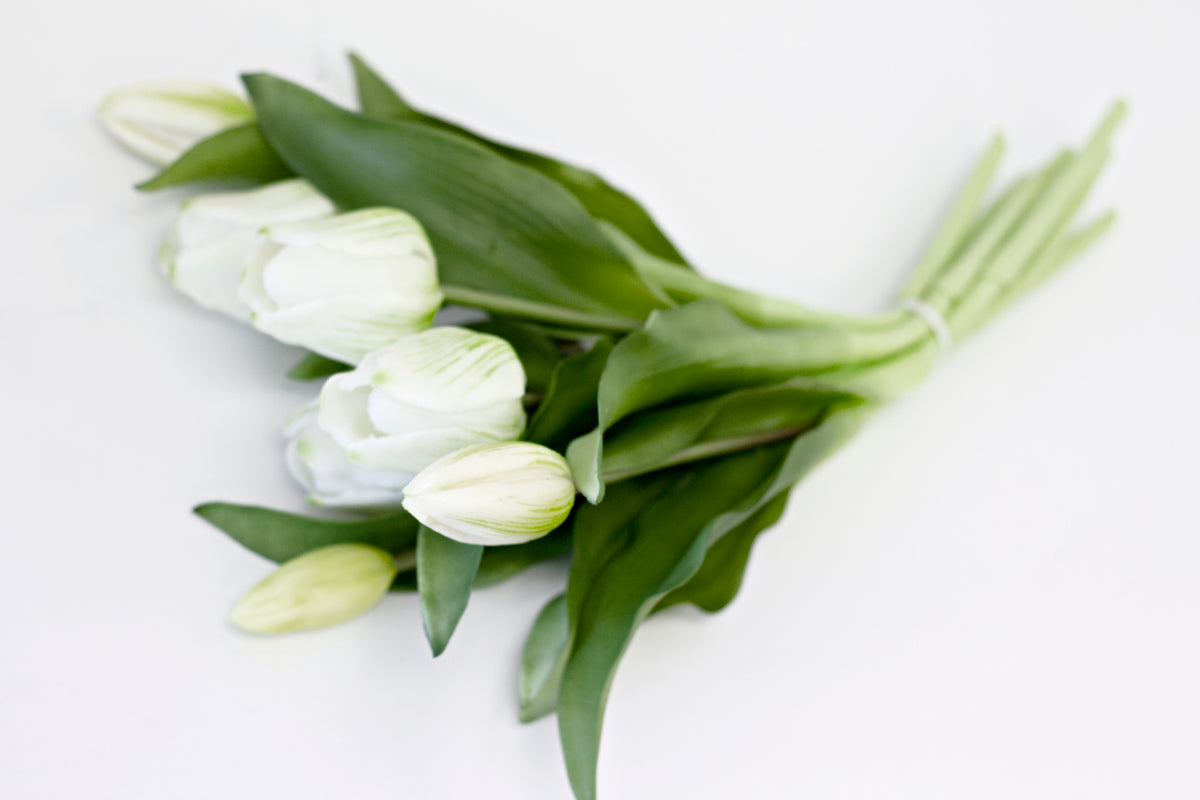 White faux tulip bunch lying flat, showing the stems and leaves