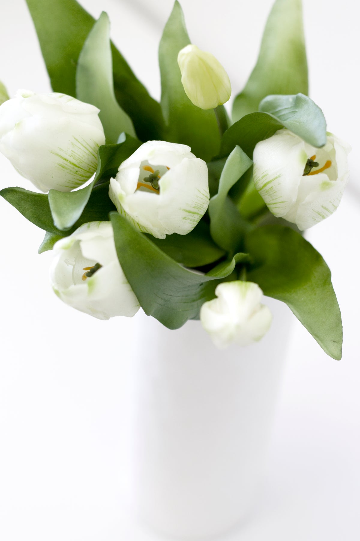 White faux tulips gathered in a white vase, close view