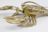 A Flux Home Lobster Ornament - Gold on a flat surface.