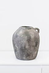 A Flux Home rustic vase w/Handle sitting on top of a white table.