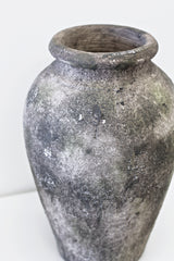 A Rustic Urn Vase by Flux Home sitting on a white surface.