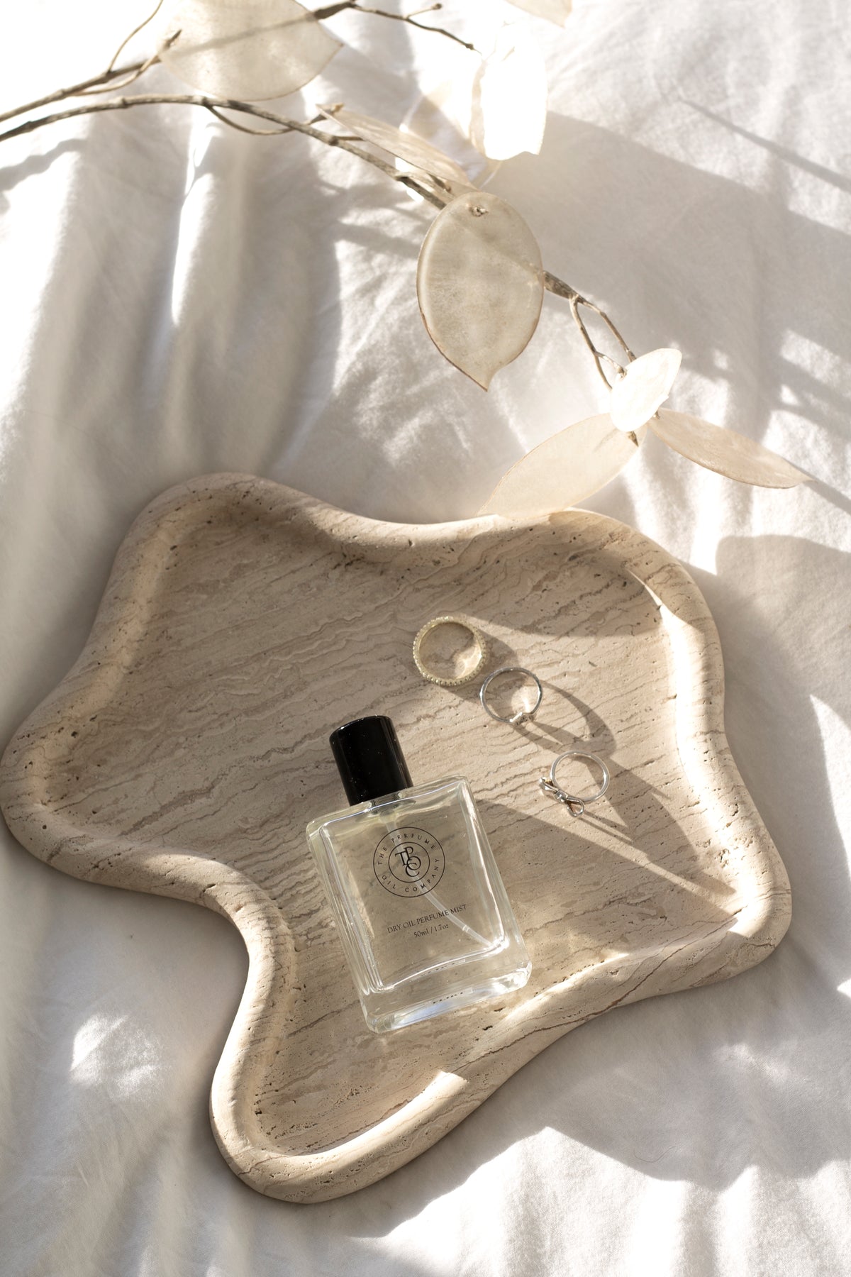 A bottle of perfume on a TRAVERTINE CURVED TRAY by Papier HQ.
