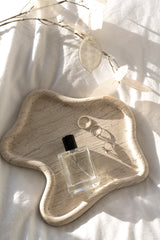 A bottle of perfume on a TRAVERTINE CURVED TRAY by Papier HQ.