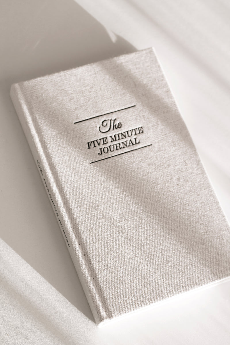 The Intelligent Change Five Minute Journal on a white surface promotes positive psychology and mindfulness.