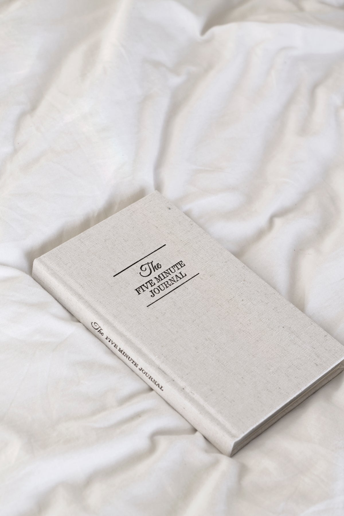 Linen Five Minute Journal lying on rumpled white bedding