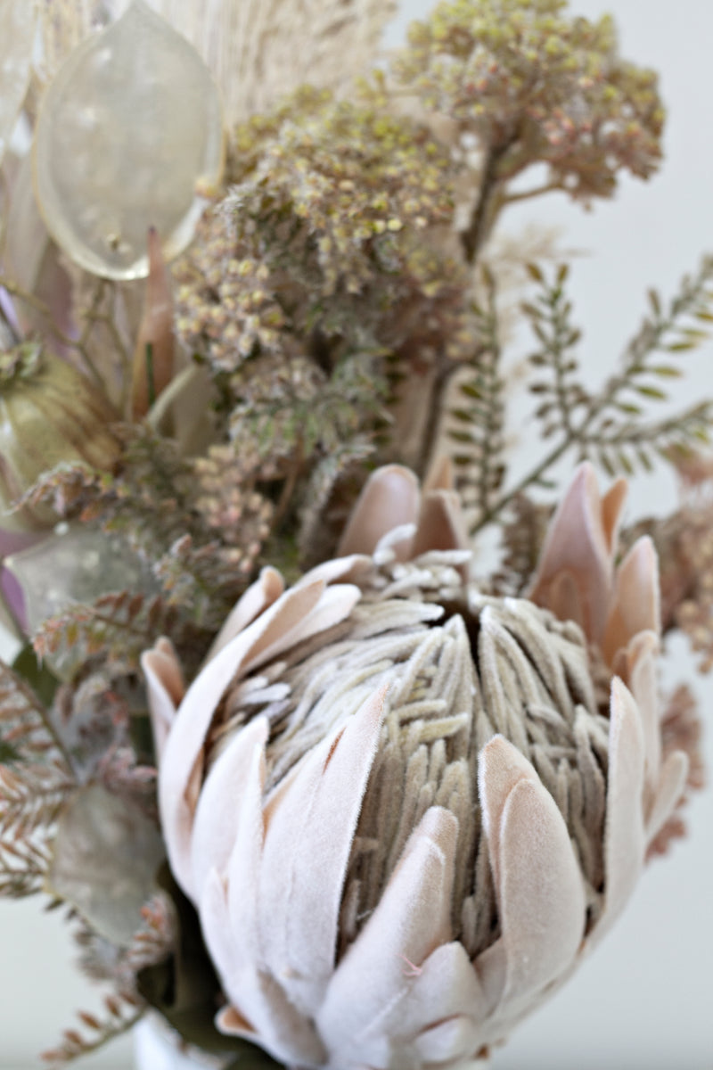 A stunning arrangement of artificial flowers, including the beautiful Artificial Flora Dried Protea - Large, showcased in an elegant vase on a table.