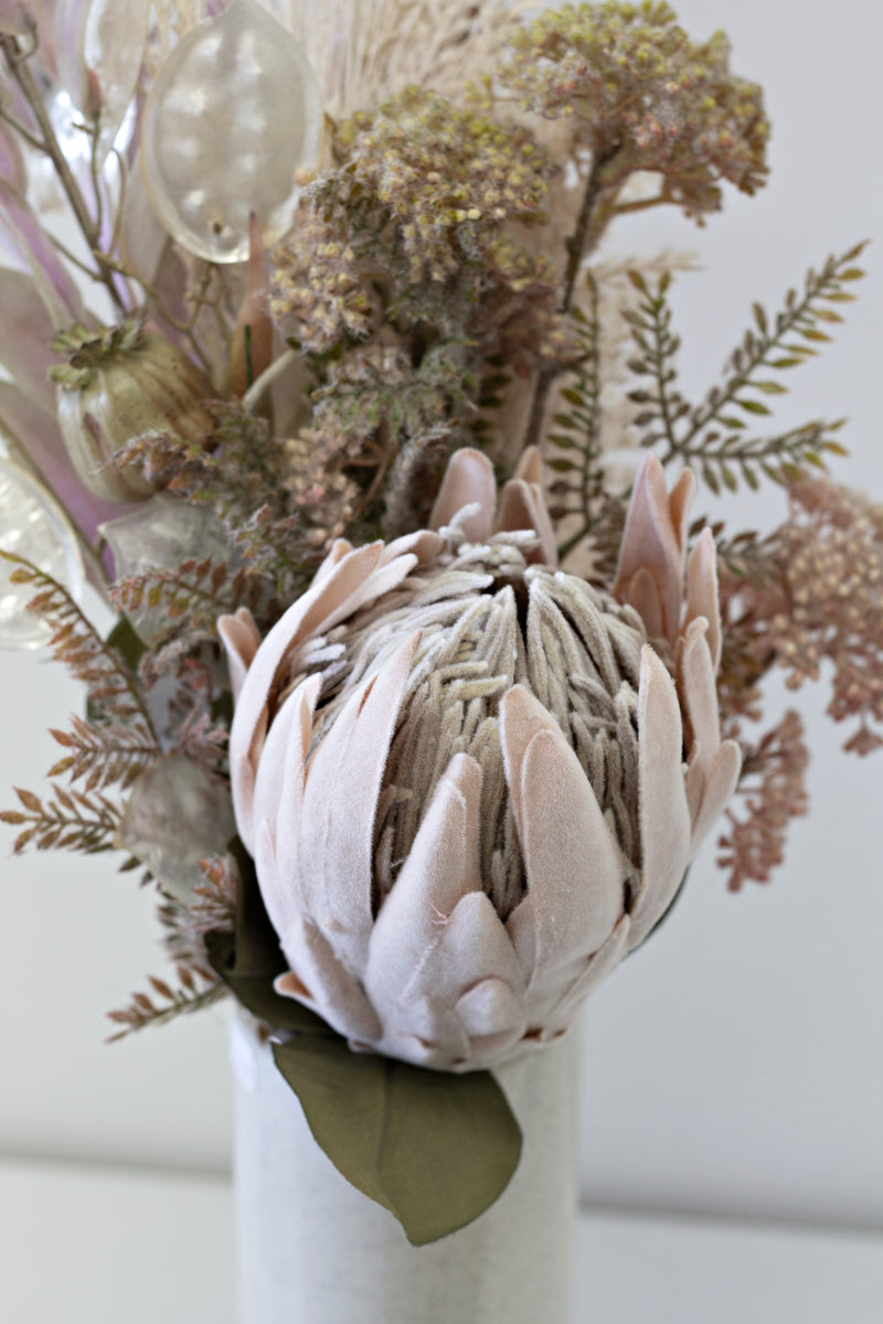 A white vase filled with beautiful dried Artificial Flora - Large Protea flowers.