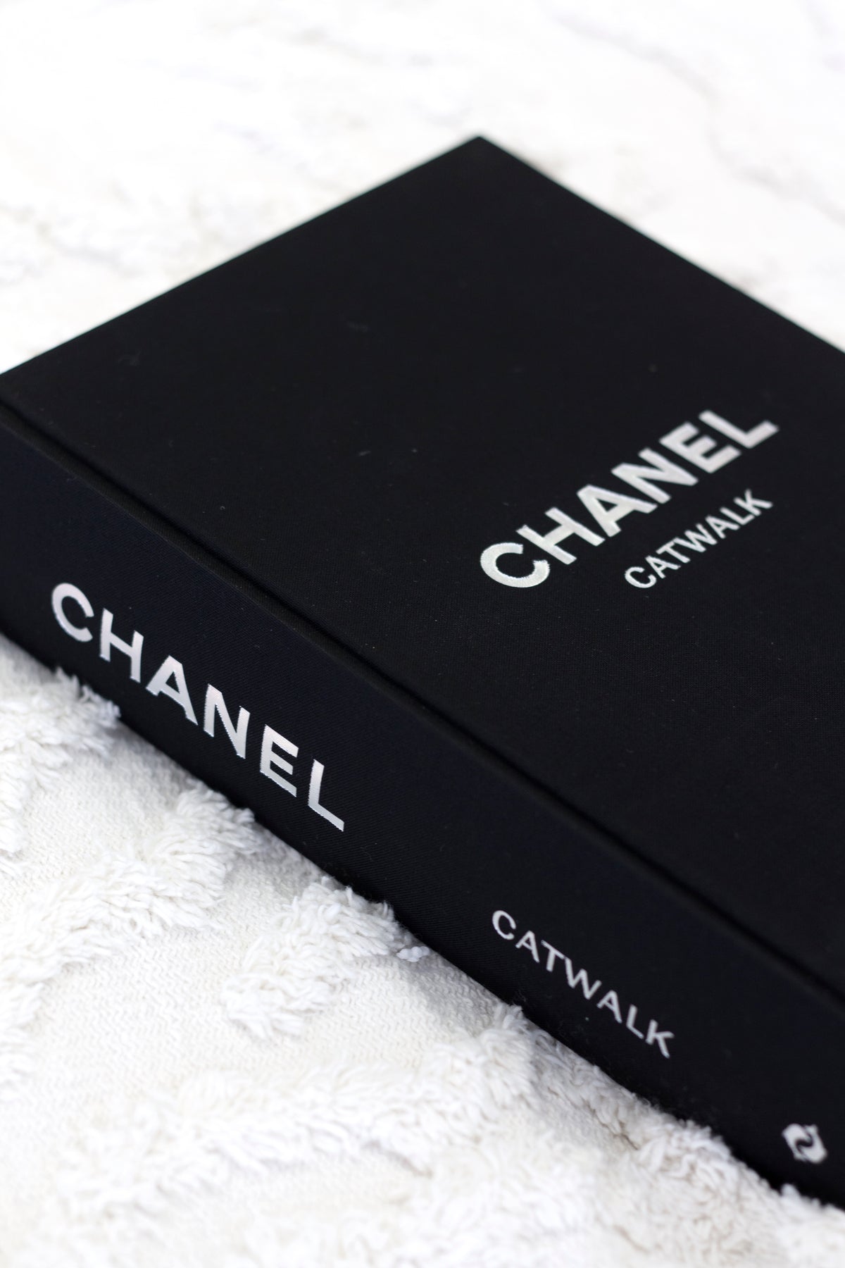 Close-up of the Chanel Catwalk spine and cover on a white textured throw