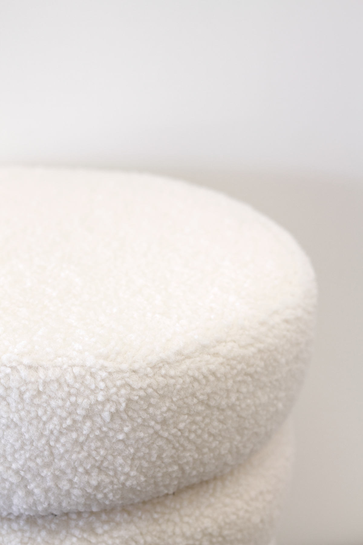 Close view of the ottoman's white boucle edge, showing the tiered seam
