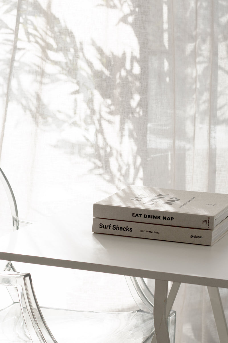 A white table with Surf Shacks Volume 2 books by Gestalten on it.