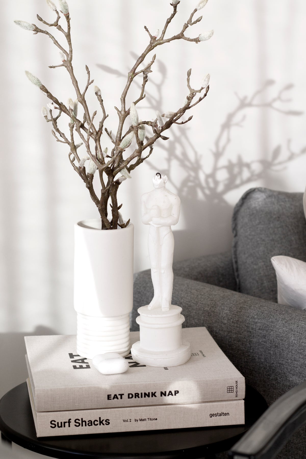 White vase of branches on a stack of Eat, Drink, Nap books