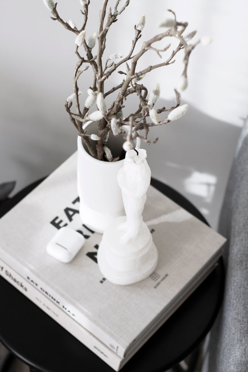 An Artificial Flora Magnolia Branch on a table next to a book.