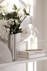 A Zakkia Polished Cylinder Vase - Silver of flowers on shelves.