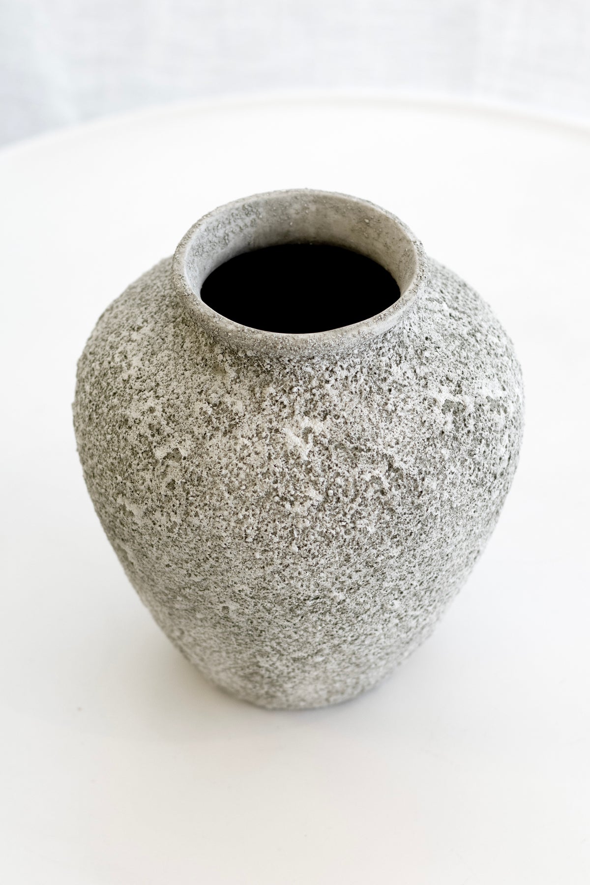 Nerina vase from above showing its dark opening and weathered sage texture on a white table