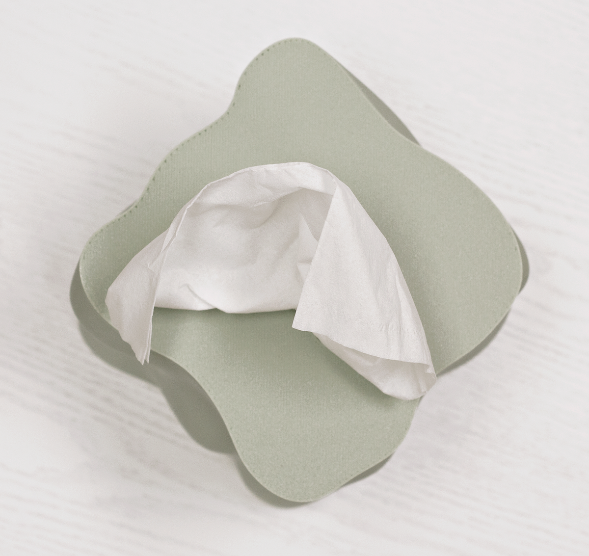 Sage green Ebb tissue box cover seen from above with a tissue pulled through the opening