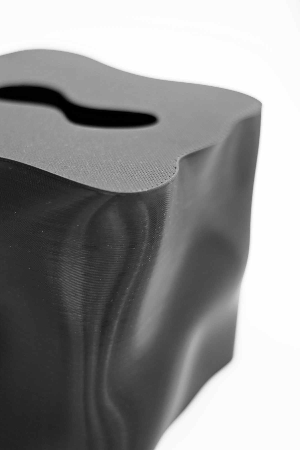Close up of the Ebb tissue box cover in black, showing the rippled surface and shaped opening