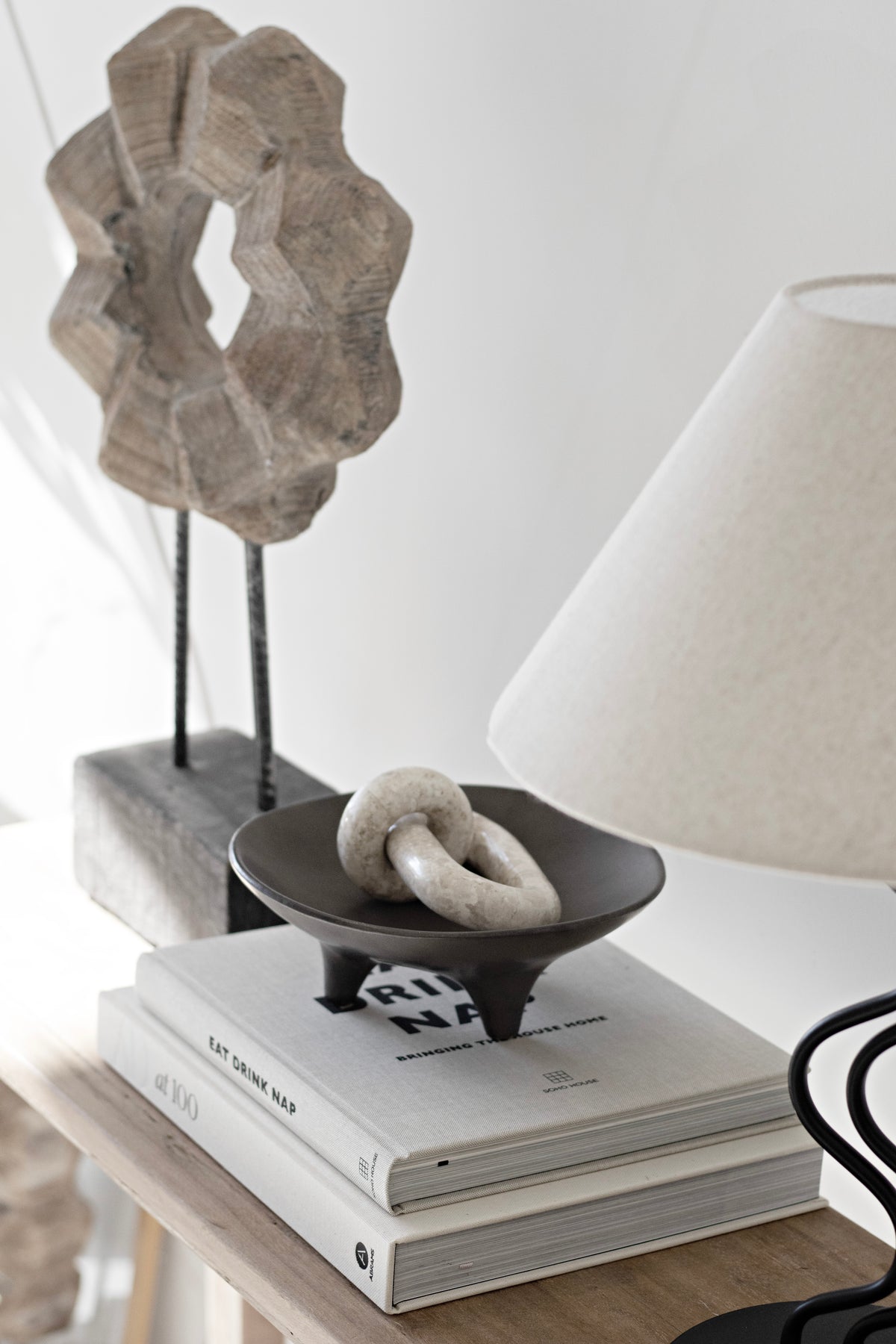 Onyx tripod plate with a white knot ornament beside a cream lampshade and stacked books