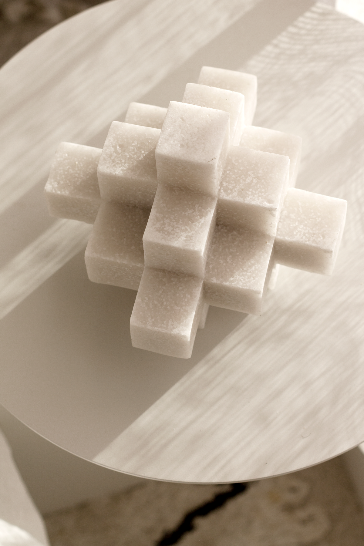 White Cubism sculpture on a round timber table in warm light